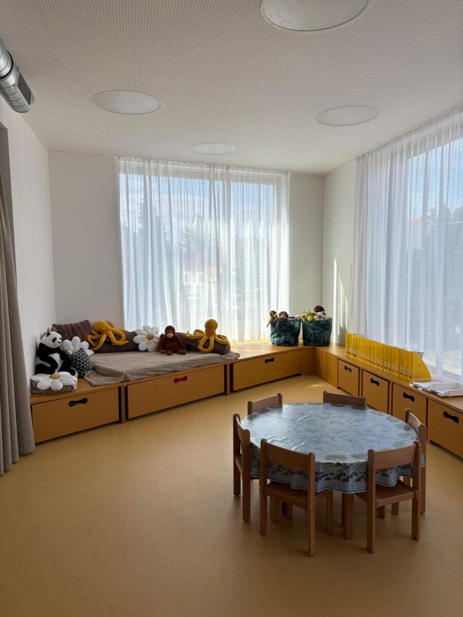 Relaxační koutek třídy s lavicí plnou plyšových hraček a kulatým stolem